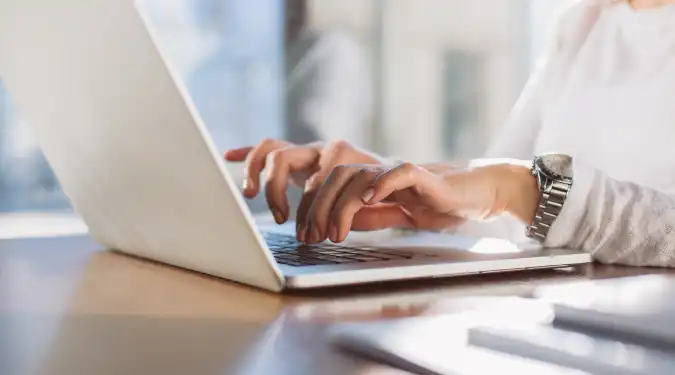 A person typing on a laptop at a desk.